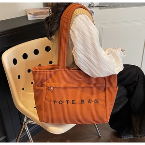 Détail du sac cabas en velours côtelé orange avec broderie noire et poche zippée pratique
