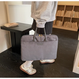 Detail view of grey suede laptop bag with dual gold zippers and stylish carrying handles