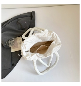 Detail view of white quilted puffer tote bag with spacious interior and zipper closure
