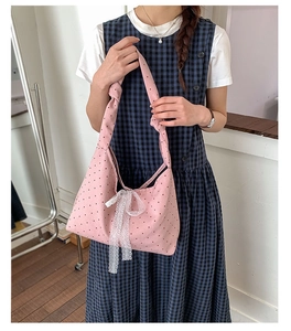 Detail of pink polka dot canvas tote bag featuring lace bow and knotted shoulder strap