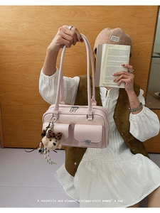 Detail of pink faux leather tote bag with silver zippers and bear plush charm accessory