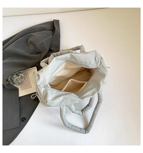 Detail view of the spacious inner compartment and interior pocket of a quilted puffer bag