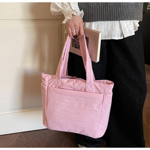 Detail view of pink quilted nylon tote bag with side pocket and sleek shoulder straps