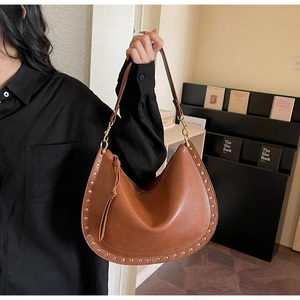Close-up of brown crescent hobo bag with gold metal rivets and knot detail