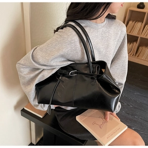 Détail du cabas en cuir verni noir avec boucle métallique et fine sangle en cuir décorative