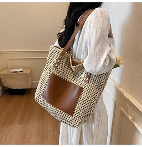 Detail of hand-woven straw tote bag featuring deep brown faux leather pocket and handles