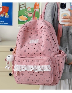 Close-up of pink corduroy backpack with bear print, lace trim and plush doll charm