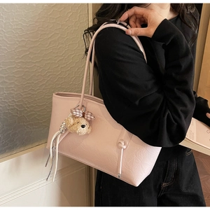 Dettaglio della borsa tote rosa con trama in ecopelle e ciondolo a forma di cucciolo