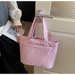Detail view of the pale pink quilted tote bag showing large front and side utility pockets