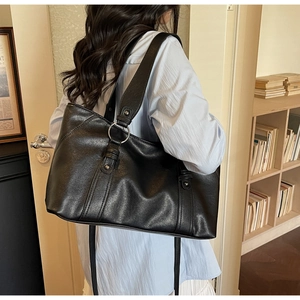 Detail of vintage pleated soft leather texture and silver ring hardware on black tote bag