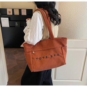 Vue détaillée de la texture du velours côtelé et de la broderie sur le sac fourre-tout