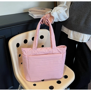 Detailed side view of pink quilted tote bag with spacious side pocket and nylon texture