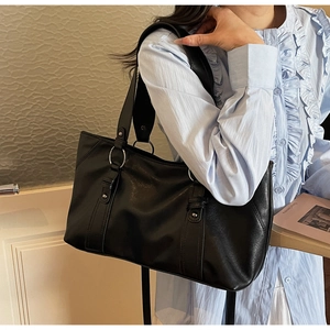 Detailed view of black vintage leather tote bag with silver metal rings and rivets