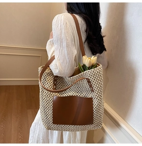 Close-up of beige woven straw tote bag with brown leather strap and front pocket detail