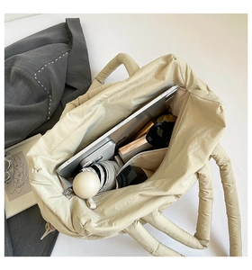 Spacious interior of beige quilted down tote bag holding laptop, umbrella and daily essentials