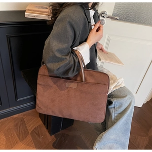 Detail of the front zipper pocket and LMER leather logo on brown suede laptop bag