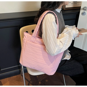 Detail of pink quilted nylon tote bag showing its lightweight puffed texture and large capacity