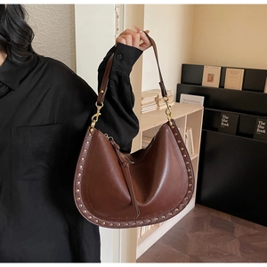 Detail of dark brown hobo bag with vintage gold rivets and leather tassel trim