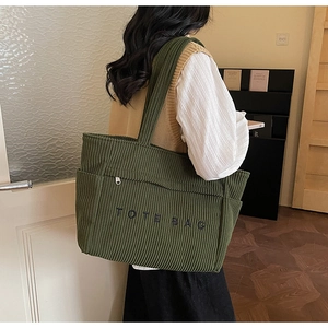 Détail du sac cabas en velours côtelé vert avec poches latérales et broderies de lettres