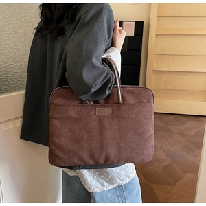 Detail of professional brown suede laptop bag held by a person in business attire