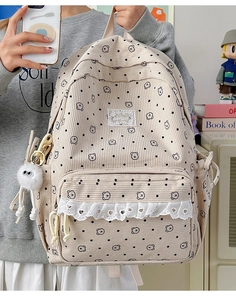 Detail view of beige corduroy backpack with cute bear print and plush charm accessory