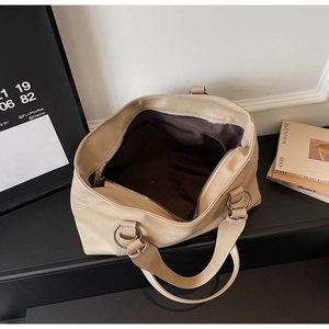 Detailed interior view of a large beige soft leather tote bag with dark lining and pocket