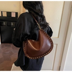 Close-up of brown leather hobo bag with vintage gold rivets and metal hardware