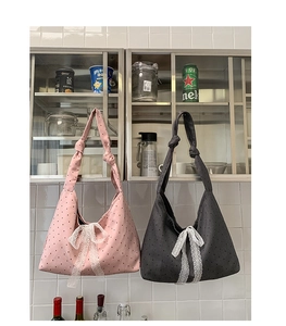 Close-up of large canvas hobo bags with polka dots and lace bows in pink and grey