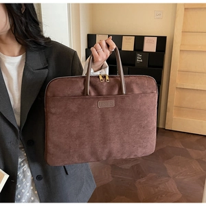 Close-up of brown suede laptop briefcase with metal double zippers and leather handles