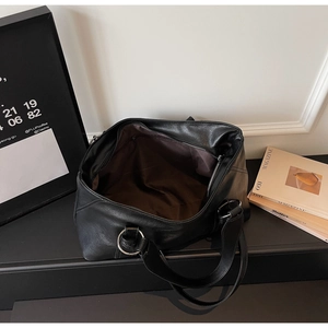 Macro detail of black leather tote with brown fabric lining and secure zipper pocket