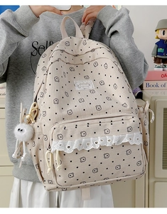 Detail of beige corduroy backpack featuring lace trim, bear prints and a plush charm