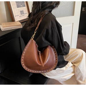 Detail view of retro brown leather crescent bag with gold rivets and tassel zipper