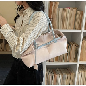 Détail du sac cabas rose en similicuir avec anses bleues sur fond de bibliothèque
