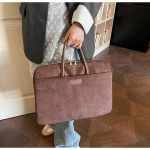 Detail view of brown suede laptop briefcase with dual gold zippers and sturdy handles