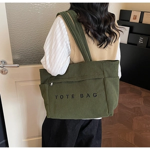 Détail du sac cabas en velours côtelé vert avec texture rayée et broderie noire