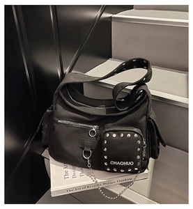 Detail of black canvas utility crossbody bag with silver rivets and multi-pocket design