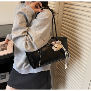 Dettaglio della borsa tote nera in ecopelle testurizzata con un ciondolo a forma di cane