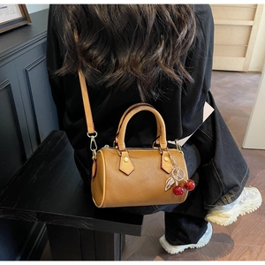 Classic monogram cylinder bag with cherry charm shown on model in stylish lifestyle setting