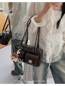 Detail view of dark brown vintage shoulder bag with front pockets and plush bear charm