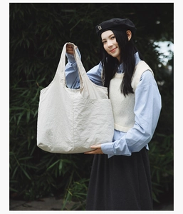 Détail du sac cabas beige en tissu texturé avec poche latérale à bouton-pression utile