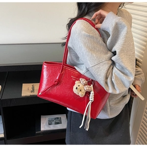 Dettaglio della borsa tote in pelle rossa con charm orsetto, nappe e logo Shante & Katie