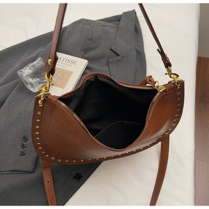 Detail of vintage brown crescent bag showing golden studs and black inner lining texture