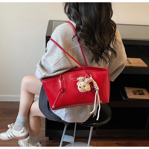 Borsa tote rossa lucida in vernice con ciondolo a forma di orso su una modella
