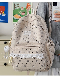 Close-up detail of beige corduroy backpack with bear print and lace heart trim