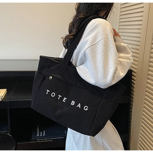 Détail du sac cabas en velours côtelé noir avec broderie blanche et poche zippée latérale
