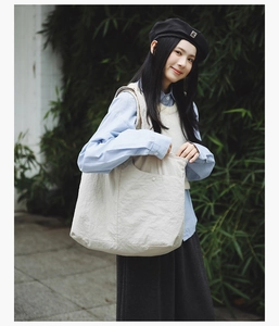 Détail d'un sac cabas minimaliste en toile blanc cassé avec une grande poche frontale