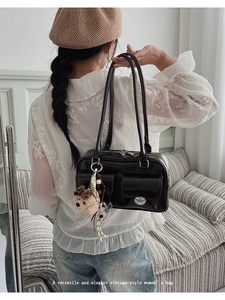 Detail of vintage dark brown handbag featuring dual flap pockets and plush bear charm