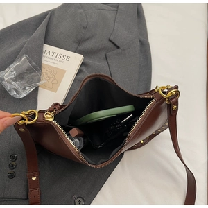 Deep brown leather shoulder bag detail showing interior storage with gold rivet accents