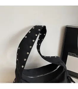 Detail of black canvas shoulder strap featuring silver round metal rivets and sturdy stitching