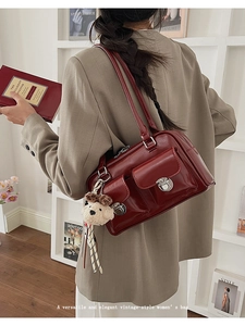 Detail of burgundy vintage shoulder bag with dual front pockets and silver twist locks